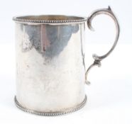 A plain form silver mug, with slightly shaped body with bead edge rim and foot and a scroll handle,