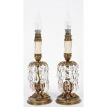 A pair of Empire style gilt metal lamps, on fish feet, with glass lustres,