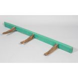 An 19th century oak saddle rack with green painted rack and three antler shaped hooks,