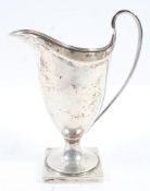 A silver helmet form cream jug with strap handle on a square pedestal foot, Chester 1864, 15cm high,