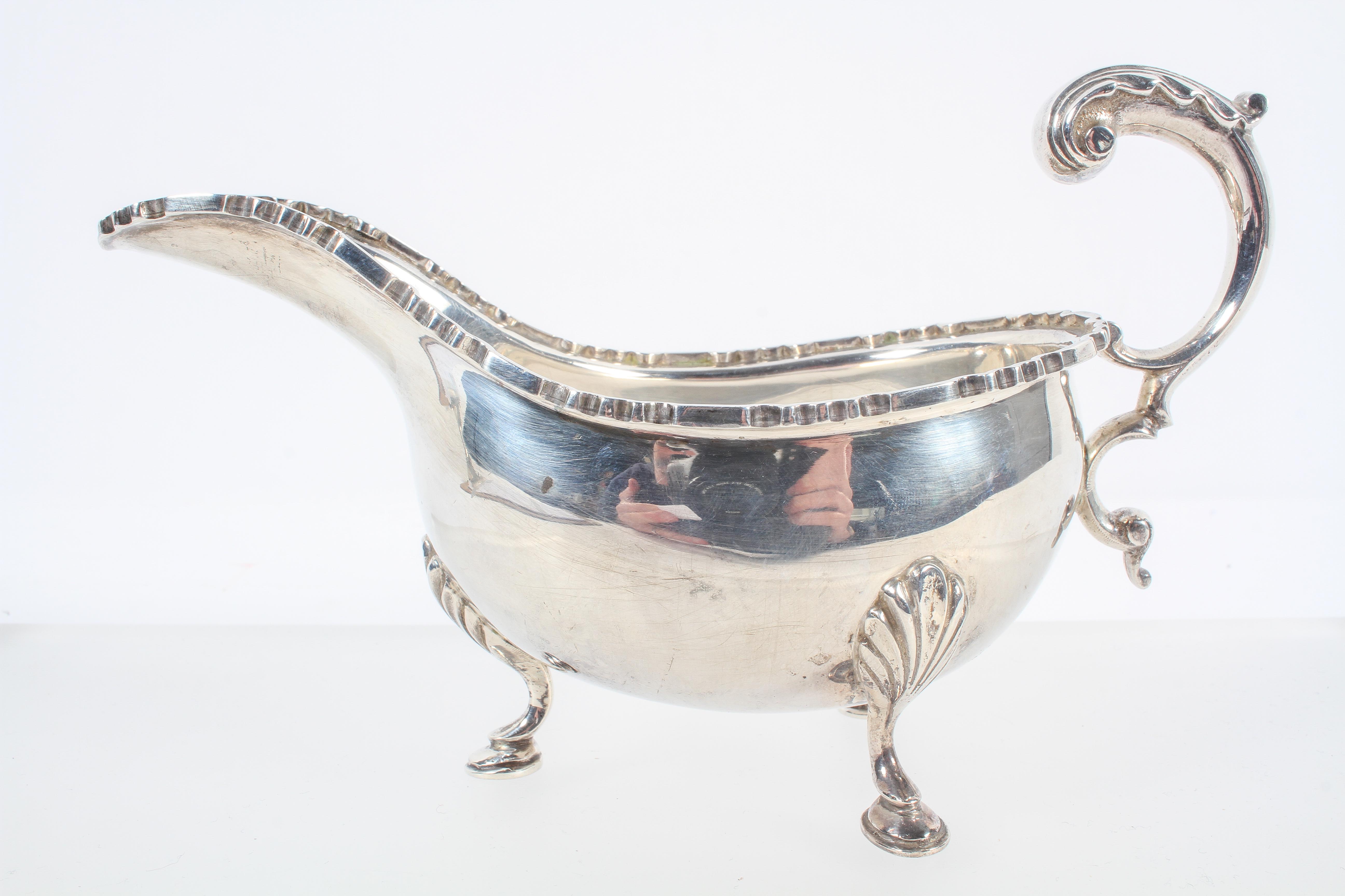 A silver sauce boat, with heavy cut card edge and an acanthus flying scroll handle,