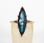 A yellow metal single stone ring. Set with a marquise cut synthetic blue spinel.