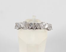 A white metal half hoop ring set with alternating round brilliant and baguette cut diamonds.