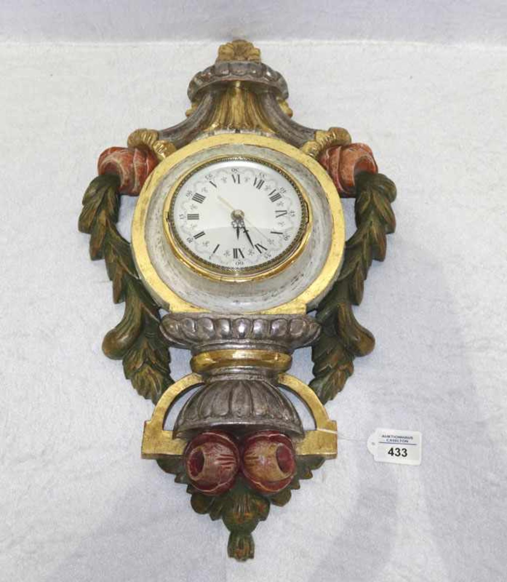 Wanduhr in geschnitztem Holzgehäuse, geschnitzt und farbig gefaßt, teils mt Blattgold, rückseitig