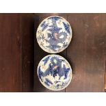 A pair of damaged antique Oriental porcelain dishes painted with an underglaze blue dragon and