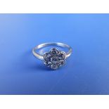 A diamond daisy cluster ring set in white metal. Finger size O/P.