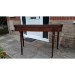 A Georgian mahogany folding tea table on slender turned legs.