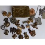 A WWI Christmas ration tin with various military cap badges.