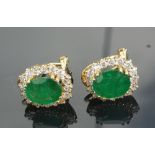 A modern pair of oval certified emerald & diamond cluster earrings, each emerald weighing