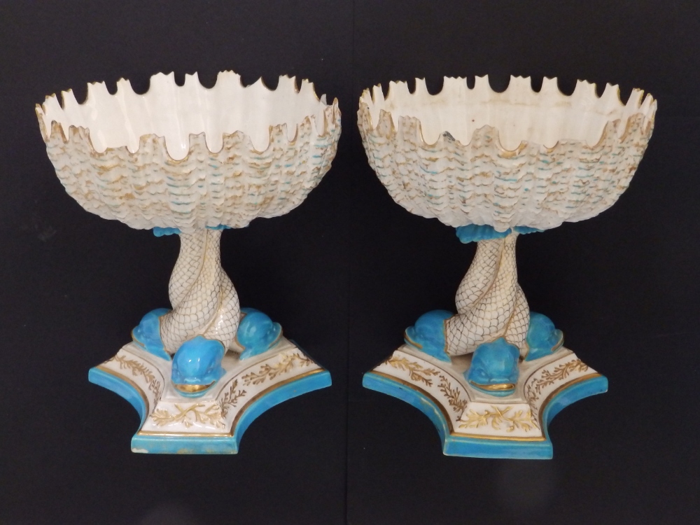 A pair of 19thC Royal Worcester porcelain circular shell-shaped bowls on triform pedestal dolphin