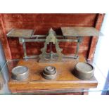 An old set of brass parcel scales including a 4lb weight and others. 14.5" across wooden base.