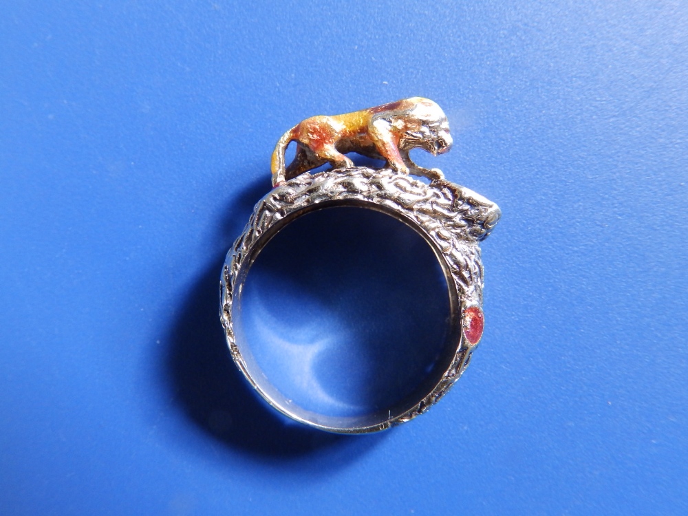 A '14' yellow metal ring modelled with a lion gazing into a red enamelled pool. Finger size N.