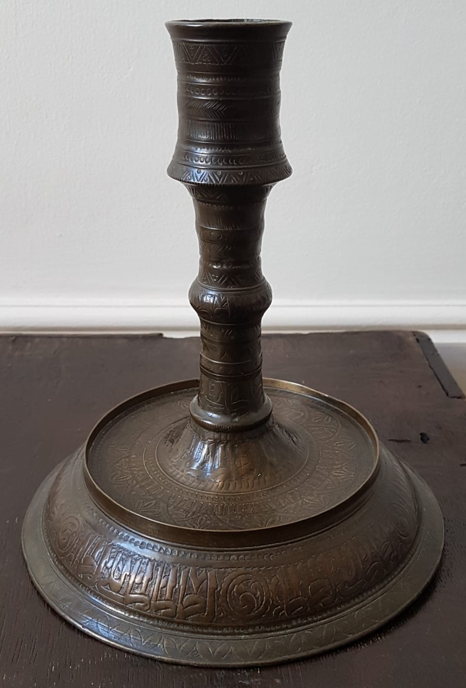 An antique Islamic copper alloy candlestick, decorated overall with stylised foliate decoration