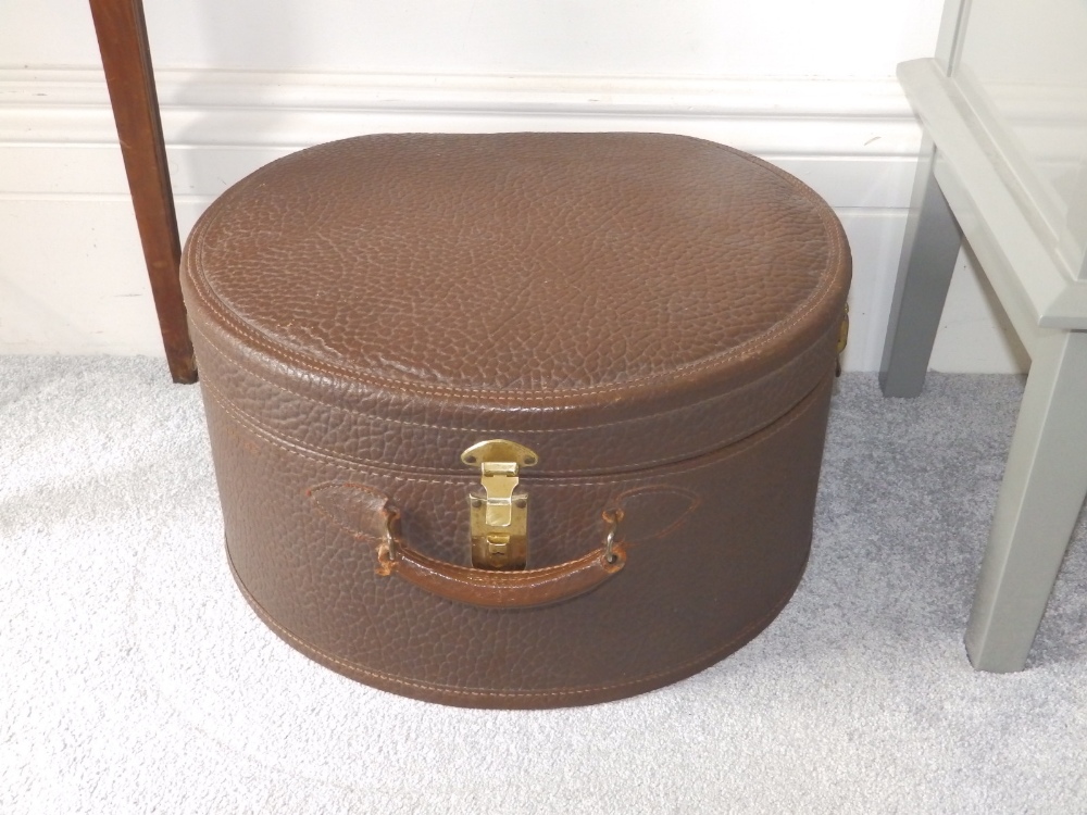 A brown 'Guaranteed Genuine Cow Hide' hat box.