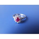 A modern oval ruby & diamond cluster ring in 18k white metal. Finger size Q/R.