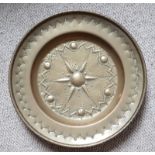 A 17thC embossed brass alms dish decorated with a serrated edge flowerhead pattern to centre, 15.75"