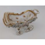 An early 20thC German porcelain pram, painted flowers with gilding and applied forget-me-not