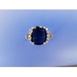 A late 20thC sapphire & diamond ring, the cushion shaped sapphire of very dark royal blue colour and