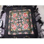 A heavy embroidered fringed black shawl, the central area decorated with a dense floral design of