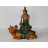 A Tang glazed pottery figure group depicting a divinity seated cross-legged on the back of a