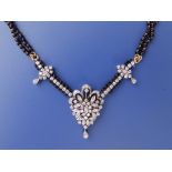 A diamond & onyx set pendant necklace, the diamond pendant of stylised openwork floral design,