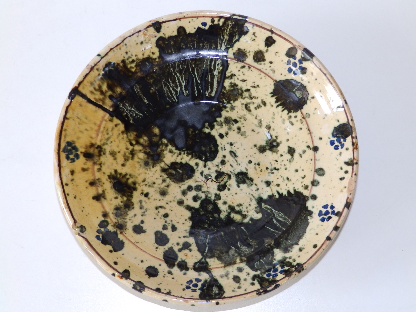 A splash glazed ceramic bowl in blue on cream ground, the moulded cavetto with thin dark brown