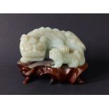 A Chinese celadon jade coloured stone carving of a Buddhistic lion with cub, 4" across, on carved