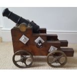 A 19thC cast iron signalling cannon mounted on stepped wooden carriage with iron mounts & bronze
