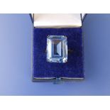 A large rectangular cut synthetic blue spinel set in yellow metal. Finger size L/M.