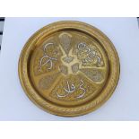 An Eastern brass circular tray with panelled decoration featuring silver & copper inlay of script