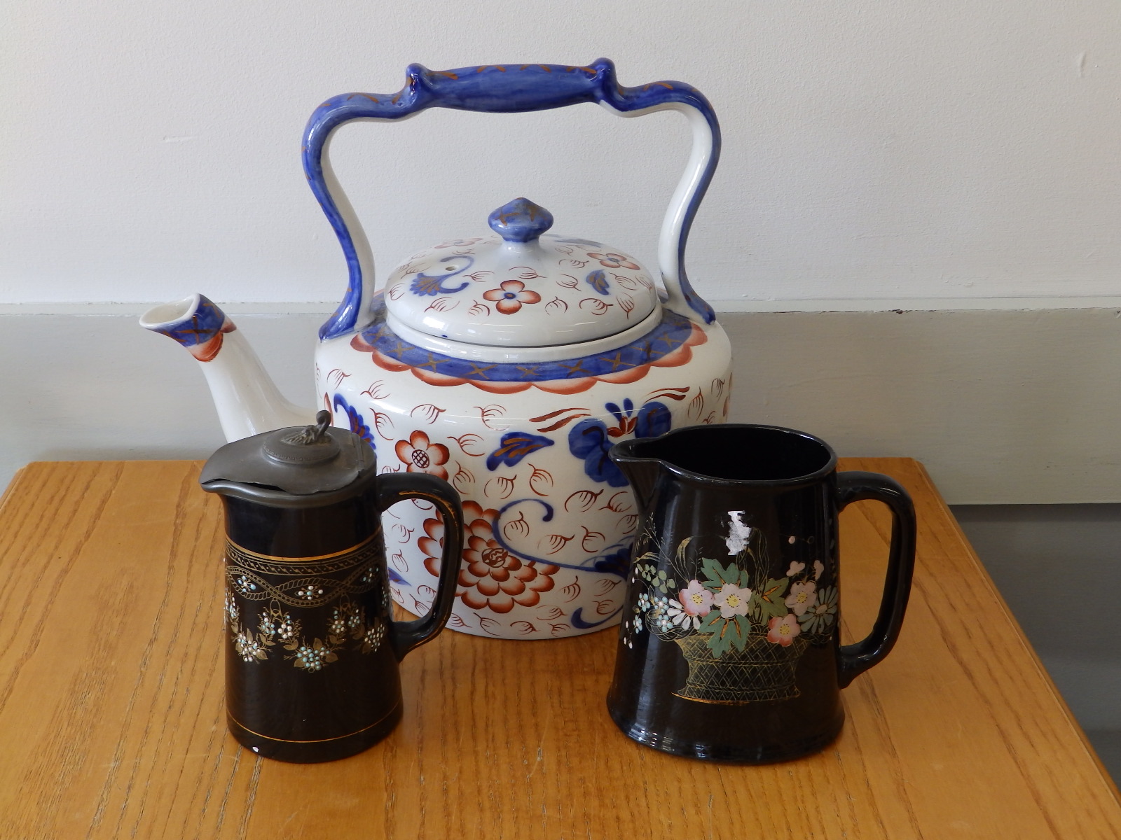 A large 'Victoria' ironstone tea kettle together with two black glazed pieces. (3)