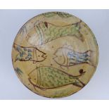 A large old studio pottery bowl, decorated with four stylised fish on a pale yellow ground, unglazed