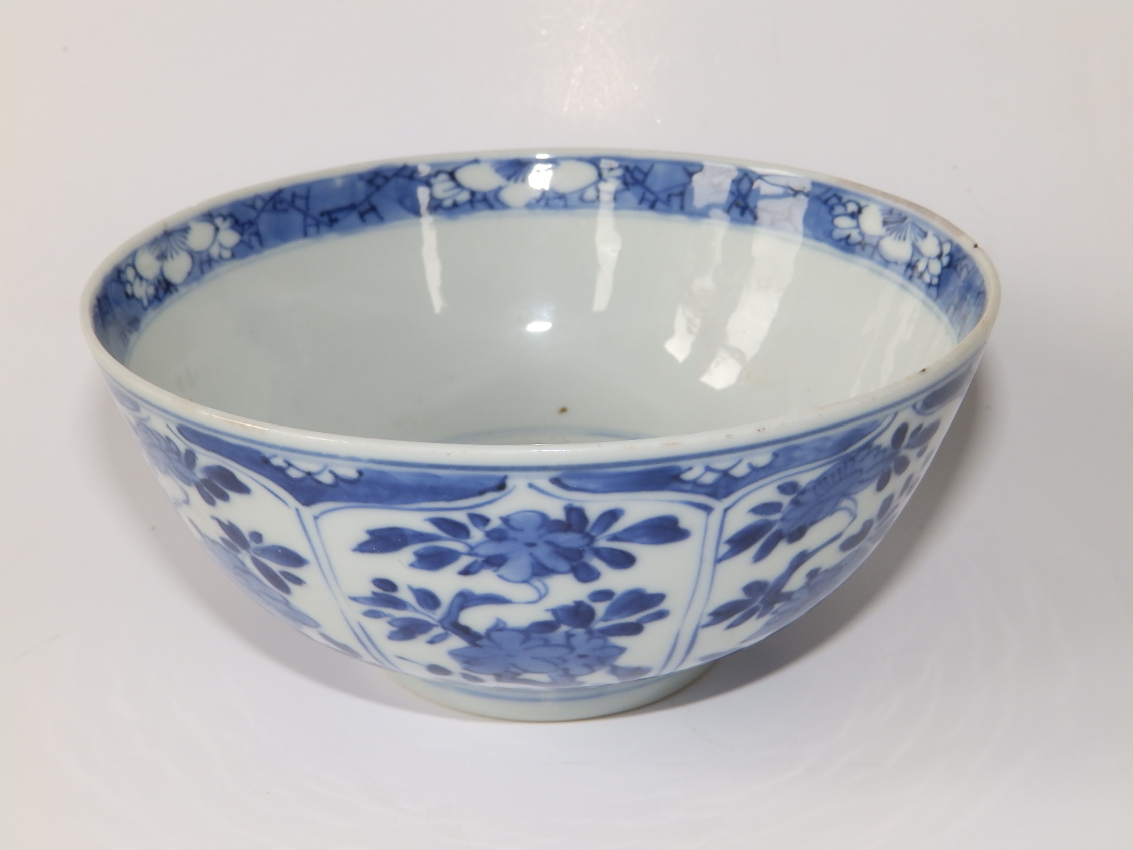 A small antique Chinese blue & white porcelain bowl, decorated with flowering foliage in lappet