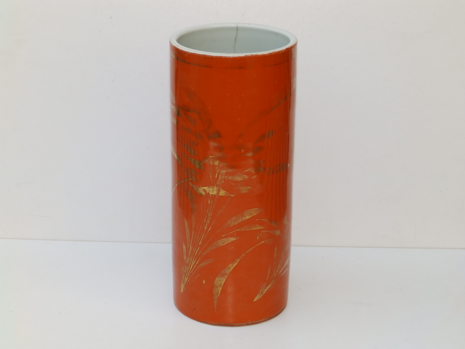 A Chinese orange ground porcelain cylindrical vase decorated in columns of gold script, orange