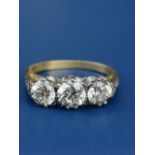 A three stone diamond ring, the brilliant cut stones in white 'PLAT' claws to yellow metal shank.