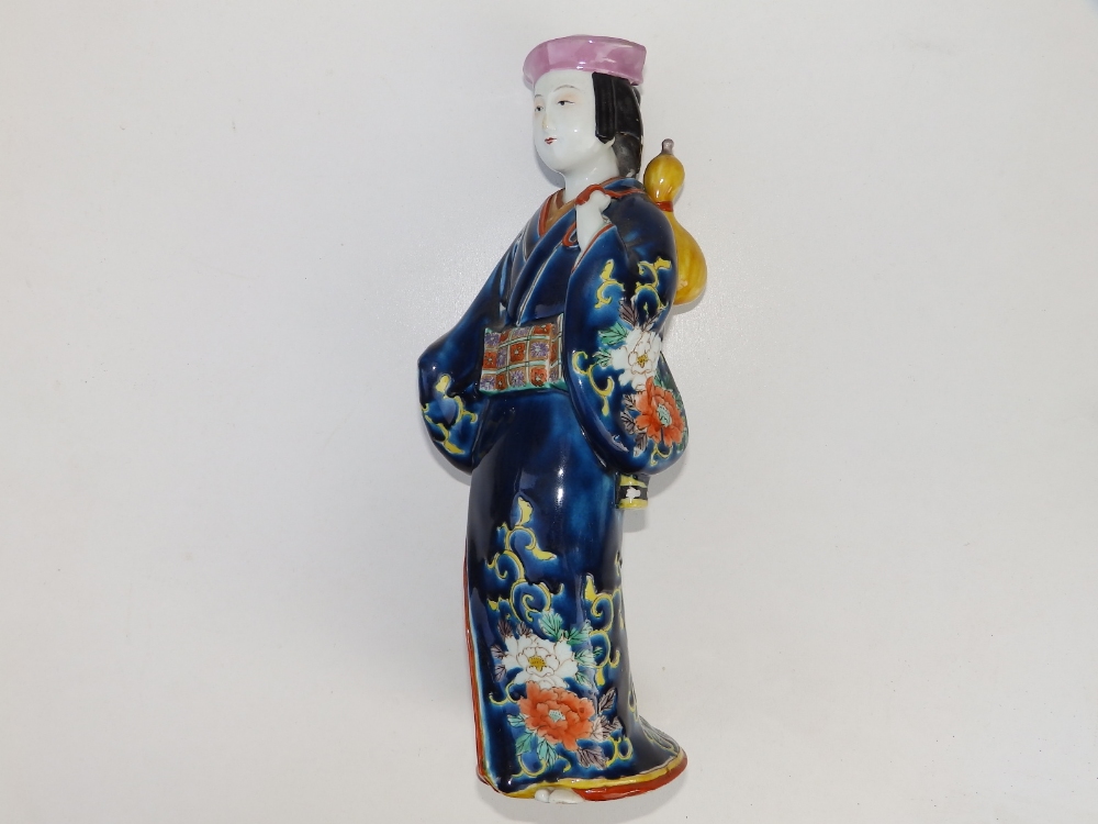 A 19thC Japanese porcelain figure of a bijin, carrying a yellow gourd over her shoulder, 11.75"