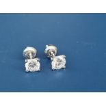 A pair of modern diamond stud earrings, the four-claw set stones in white '14k' metal, with screw-on