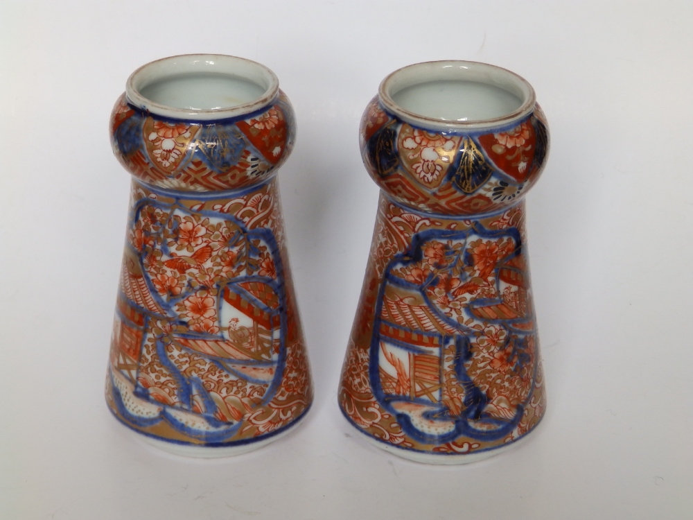 A small pair of Imari porcelain vases, of tapering shape with bulbous necks, three rows of script to