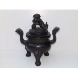 An antique Chinese bronze covered censer, the cover surmounted by a Buddhistic lion, the rounded