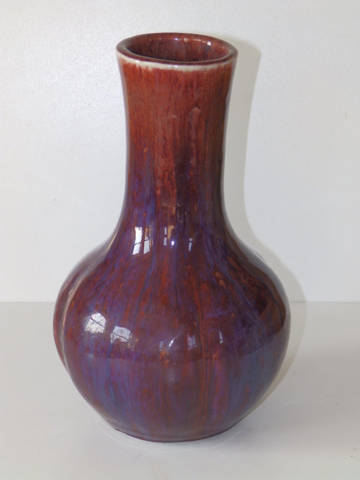 A thickly potted Chinese Sang de Boeuf porcelain bottle vase, decorated in red & purple, the body