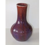 A thickly potted Chinese Sang de Boeuf porcelain bottle vase, decorated in red & purple, the body