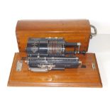 A Britannic calculator on mahogany base with cover, by Muldivo Calculating Machine Co., with