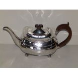 A plain Regency silver teapot of London shape, with wooden loop handle and finial, on ball feet -