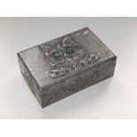 A wooden cigarette box decorated in embossed sheet pewter in the Arts & Crafts style to show the