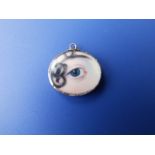 A Georgian oval painted miniature depicting a lady's eye with hair, in a glazed gold pendant case,