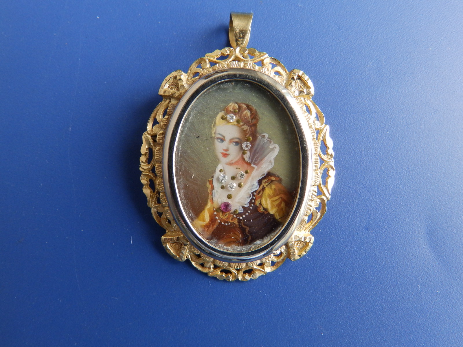 An 18ct gold brooch/pendant set with an oval painted miniature of a lady being set with tiny diamond