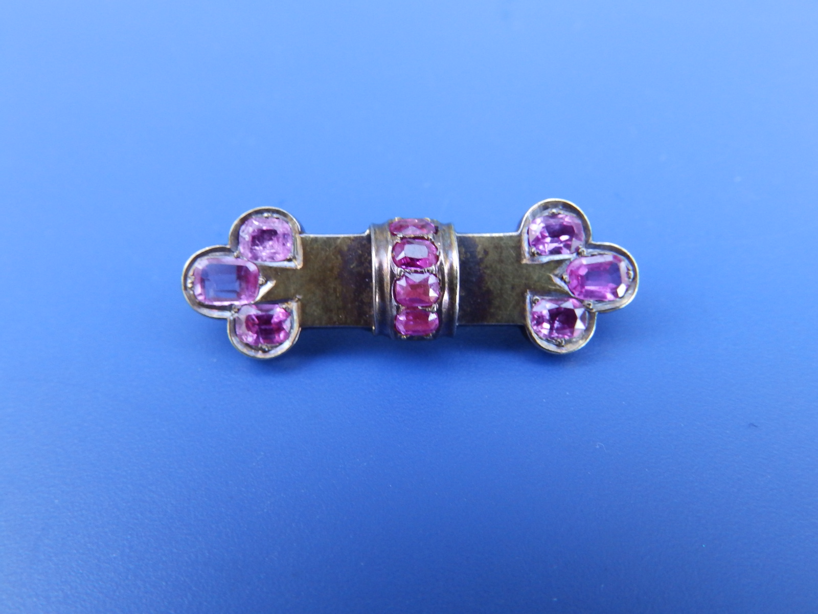 A Victorian gold brooch set with pink rubies, 1.3".