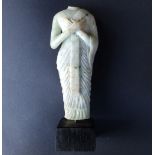 A Chinese celadon jade figure after the antique, depicting a headless figure in robe with hands