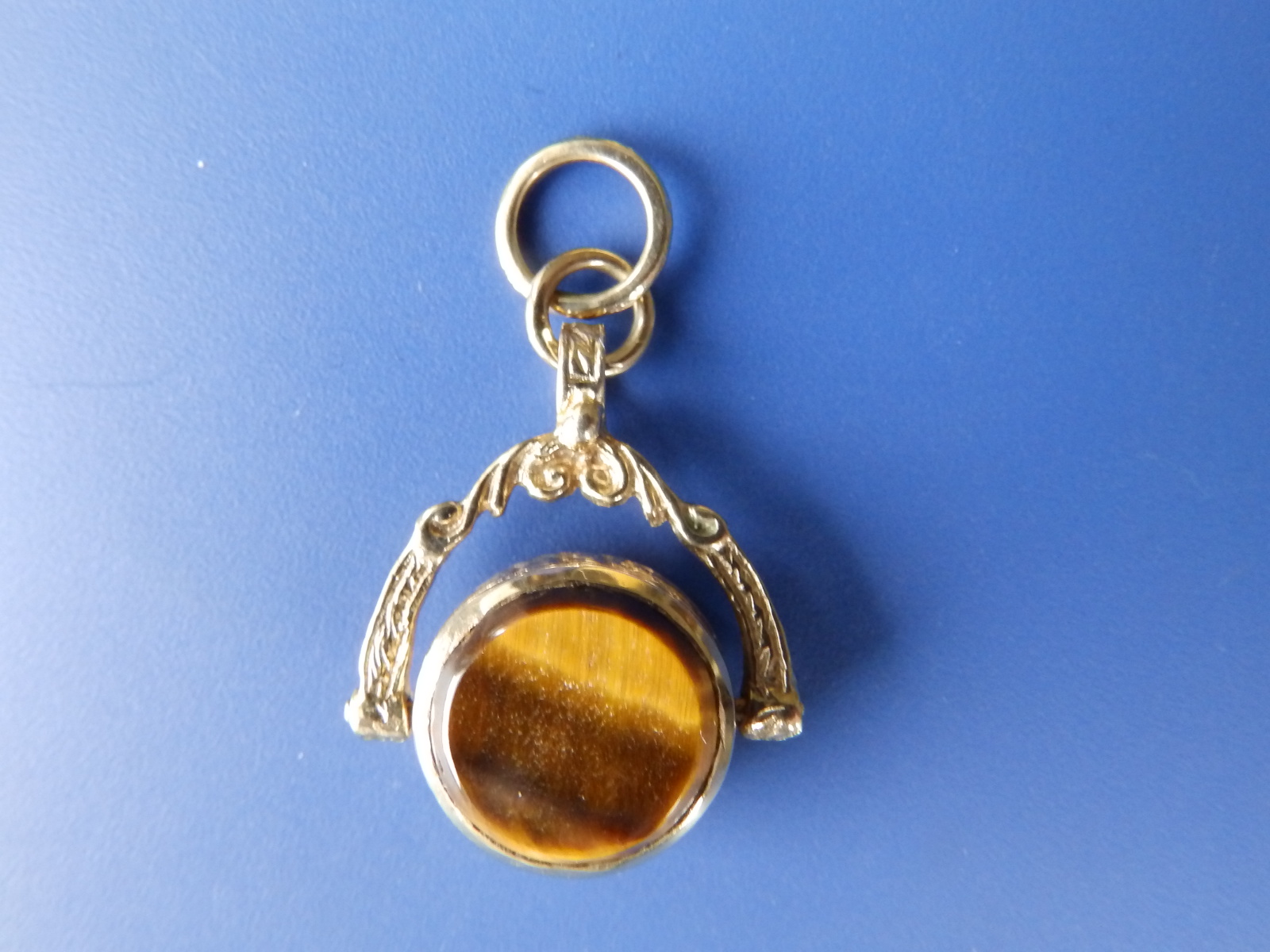 A small revolving fob seal set with a tiger's eye to one side in yellow metal.