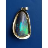 A black opal pendant of polished free-form, claw set within a gold mount, testing as 18ct, the